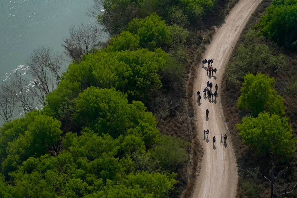 (Julio Cortez | AP) Migrants walk on a dirt road after crossing the U.S.-Mexico border, Tuesday, March 23, 2021, in Mission, Texas.