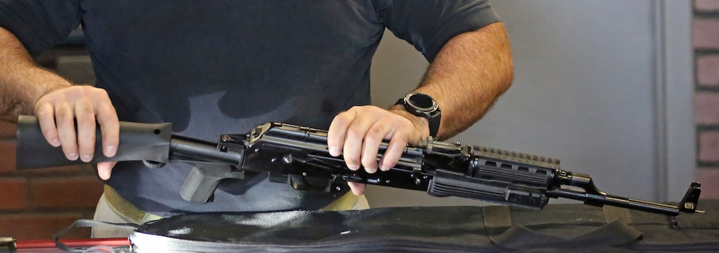 Clark Aposhian, chairman of the Utah Shooting Sports Council, attaches a little-known device called a "bump stock" to a semi-automatic rifle at the Gun Vault store and shooting range Wednesday, Oct. 4, 2017, in South Jordan, Utah. Las Vegas shooter Stephen Paddock bought 33 guns within the last year, but that didn't raise any red flags. Neither did the mountains of ammunition he was stockpiling, or the bump stocks found in his hotel room that allow semi-automatic rifles to mimic fully automatic weapons. (AP Photo/Rick Bowmer)