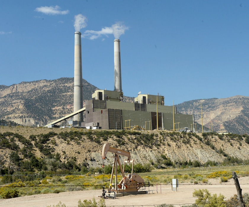 In this Sept. 8, 2015 photo, a natural gas rig pumps away in the foreground of the coal-fired Huntington Power Plant west of Huntington, Utah. (Al Hartmann/The Salt Lake Tribune via AP)