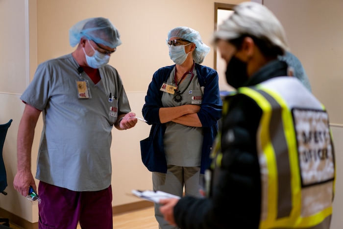 Team Rubicon volunteers, from left, Dennis Grooms, an EMT from St. Louis, Cindy Robison, a U.S. Air Force veteran and nurse from Colorado Springs, Colo., and Christra McDermont, a U.S. Navy veteran from Los Angeles, and operation section chief, gather in the emergency room during a lull at the Kayenta Health Center on the Navajo reservation in Kayenta, Ariz., on April 18, 2020. The reservation has some of the highest rates of coronavirus in the country. Team Rubicon is helping with medical operations as cases of COVID-19 surge. (AP Photo/Carolyn Kaster)