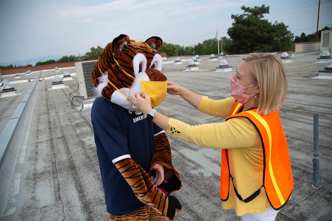 (Francisco Kjolseth  |  The Salt Lake Tribune)  Home of the Cubs, Canyon View Elementary school mascot Bennie, played by PTA president Emily Weigel gets her mask adjusted, making sure it covers her nose and mouth by school principal Kierstin Draper as they get ready to greet students back to school from the roof of the school. It was the first day of classes for the Canyons School District on Monday, August 24, 2020.