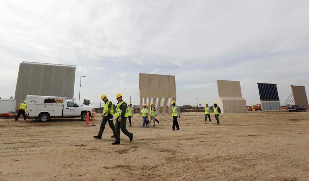 (Gregory Bull | Associated Press file photo) In this Oct. 19, 2017 file photo, people pass border wall prototypes as they stand near the border with Tijuana, Mexico, in San Diego.  A U.S. official says recent testing of prototypes of President Donald Trump's proposed wall with Mexico found their heights should stop border crossers. U.S. tactical teams spent three weeks trying to breach and scale the models in San Diego. An official with direct knowledge of the results said they point to see-through steel barriers topped by concrete as the best design. The official spoke to The Associated Press on condition of anonymity because the information is not authorized for release.