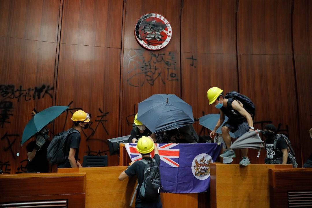 (Kin Cheung | AP Photo) Protesters put a Hong Kong colonial flag and deface the Hong Kong logo at the Legislative Chamber after break in to protest against the extradition bill in Hong Kong, Monday, July 1, 2019. The extradition law has aroused concerns that this legislation would undermine the city's independent judicial system as it allows Hong Kong to hand over fugitives to the jurisdictions that the city doesn't currently have an extradition agreement with, including mainland China, where a fair trial might not be guaranteed.