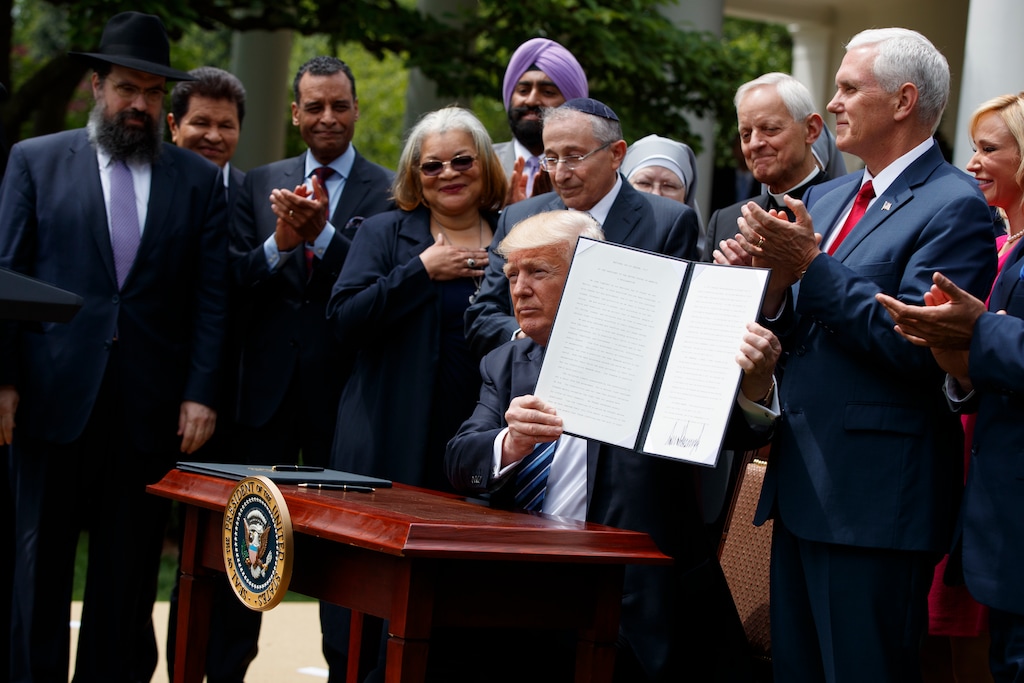 (AP Photo/Evan Vucci) In this May 4, 2017, photo, President Donald Trump holds up a signed executive order aimed at easing an IRS rule limiting political activity for churches in the Rose Garden of the White House in Washington.