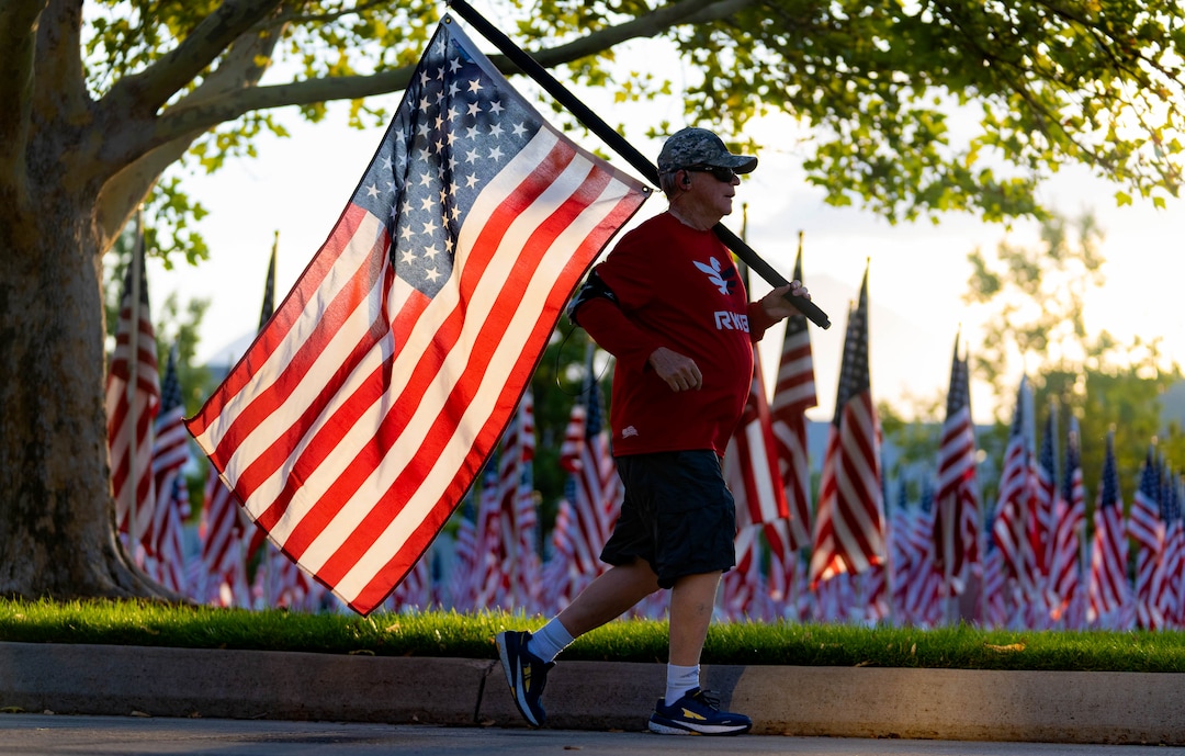 (Francisco Kjolseth | The Salt Lake Tribune) Master Sergeant Colin Green, a veteran of Kuwait, Iraq and Afghanistan runs the American flag as the sun rises on Saturday, Sept. 11, 2021, at the Utah Healing Field in Sandy, part of the nonprofit Colonial Flag Foundation, who posted 3,000 flags to honor the fallen. The display is free to the public and open now through Sept. 13.