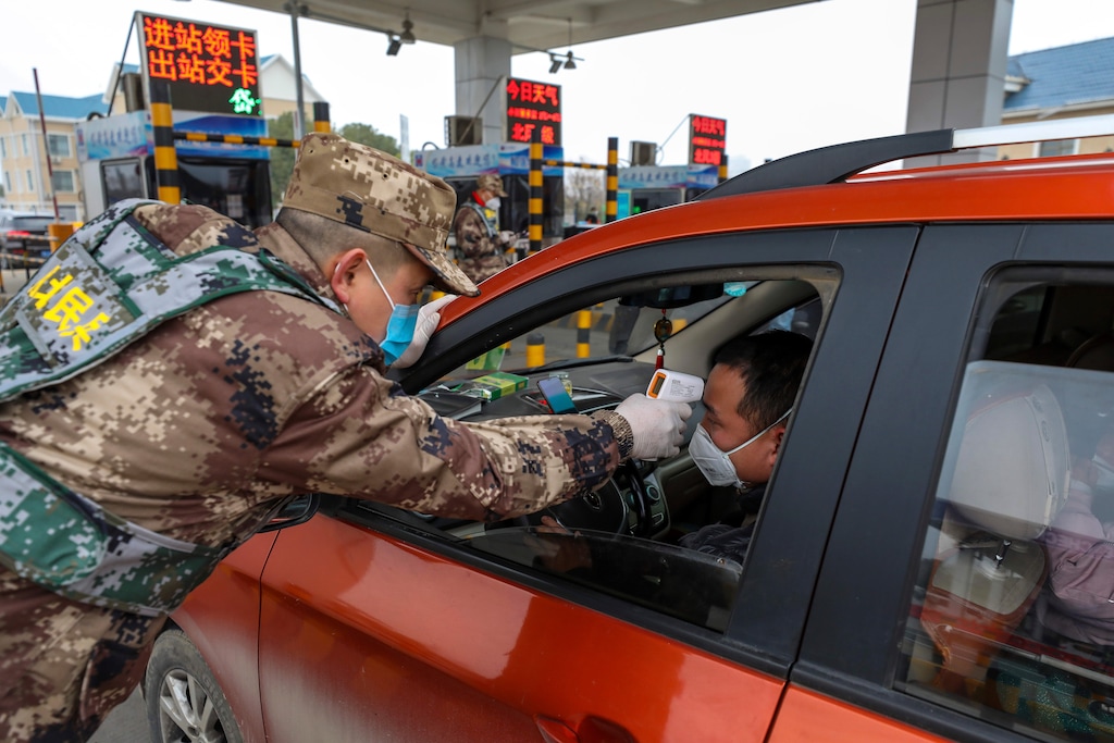 (Chinatopix | AP) A militia member uses a digital thermometer to take a driver's temperature at a checkpoint at a highway toll gate in Wuhan in central China's Hubei Province, Thursday, Jan. 23, 2020. China closed off a city of more than 11 million people Thursday in an unprecedented effort to try to contain a deadly new viral illness that has sickened hundreds and spread to other cities and countries amid the Lunar New Year travel rush.
