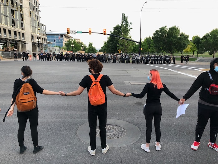 (Francisco Kjolseth  |  The Salt Lake Tribune) Protesters hold hands across the street from a line of police during demonstrations on Monday, June 1, 2020.