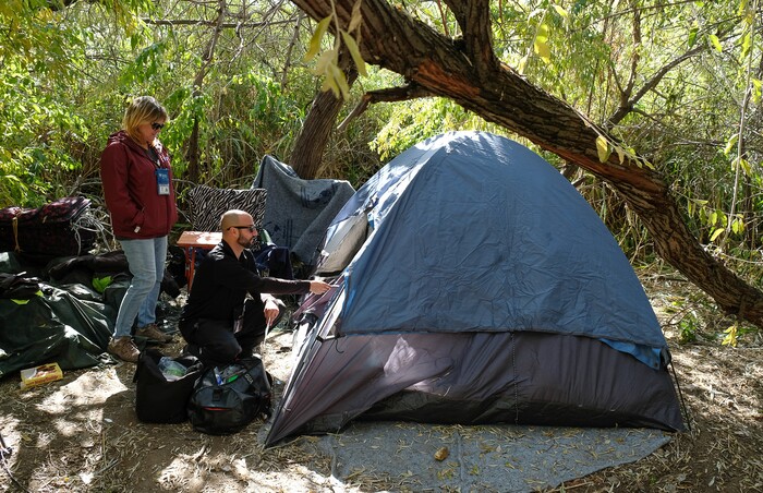 (Francisco Kjolseth  |  The Salt Lake Tribune)  Machele Nieto, a homeless outreach worker with Volunteers of America tags along with Patrick Rezac of One Voice Recovery who provides a needle exchange program for a homeless man in a tent who did not want to be identified. The two teams were making the rounds with the homeless community along the Jordan River offering support and services. 