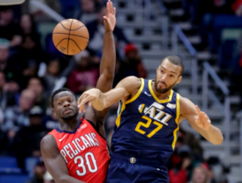Utah Jazz center Rudy Gobert (27) passes while being guarded by New Orleans Pelicans center Julius Randle (30) and guard Elfrid Payton (4) in the first half of an NBA basketball game in New Orleans, Wednesday, March 6, 2019. (AP Photo/Scott Threlkeld)
