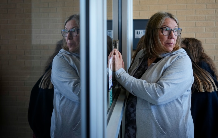 (Bethany Baker | The Salt Lake Tribune) Linda DiMaio holds her phone up to the glass near a door to Payson High School after at a charity event to commemorate the 40th anniversary of the movie "Footloose" in Payson on Saturday, April 20, 2024.