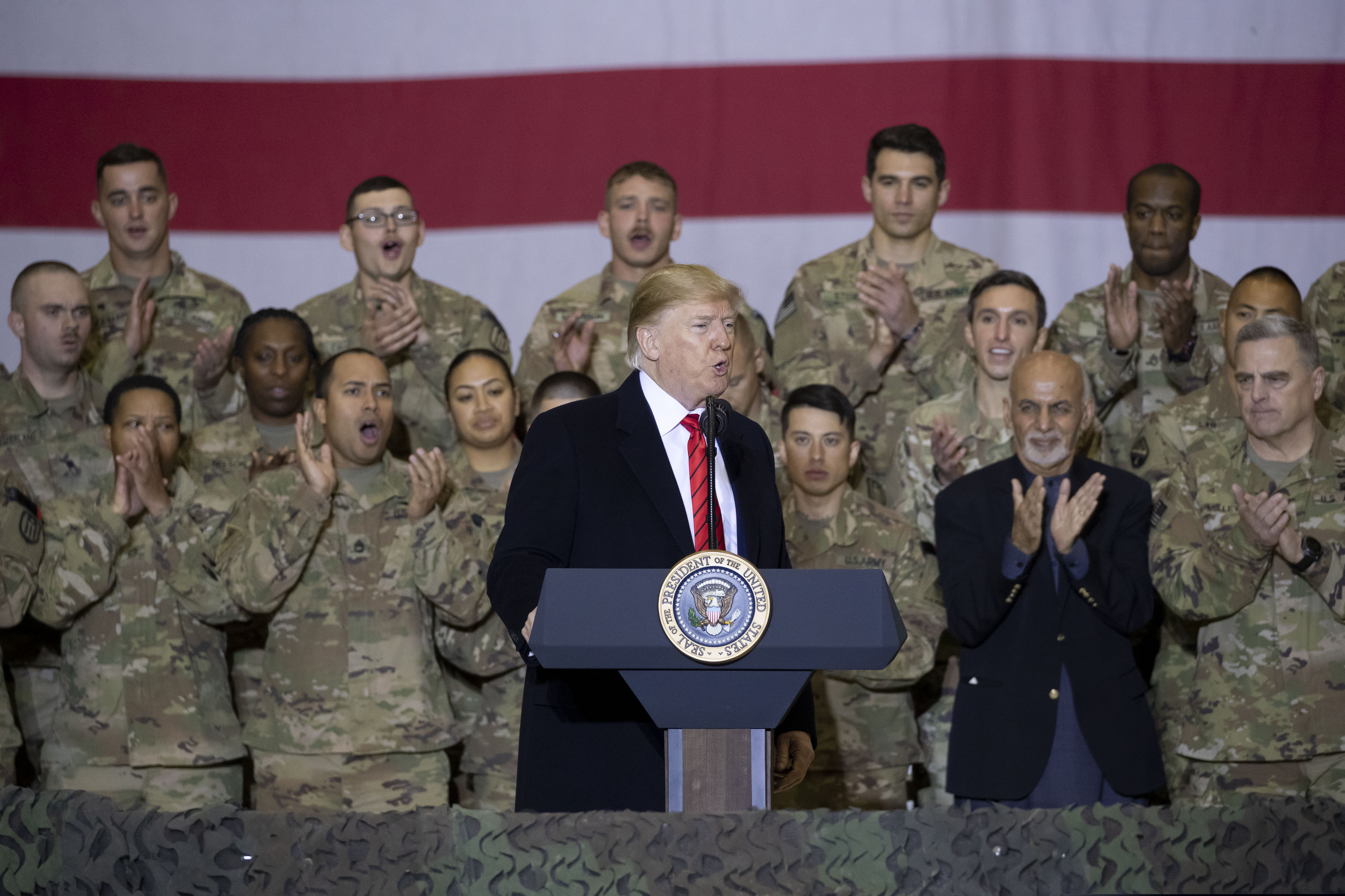 (Alex Brandon | AP) President Donald Trump, center, with Afghan President Ashraf Ghani, second from the right, and Joint Chiefs Chairman Gen. Mark Milley, right, while addressing members of the military during a surprise Thanksgiving Day visit, Thursday, Nov. 28, 2019, at Bagram Air Field, Afghanistan.