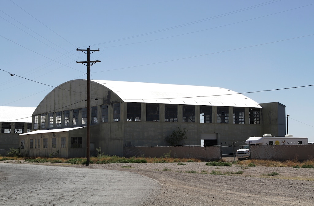 This Wednesday, May 22, 2019, photo shows a World War II-era bomber hanger in Deming, N.M. A surge of asylum-seeking families has been straining cities along the southern U.S. border for months, but now the issue is flowing into cities far from Mexico, where immigrants are being housed in an airplane hangar and rodeo fairgrounds and local authorities are struggling to keep up with the influx. (AP Photo/Cedar Attanasio)