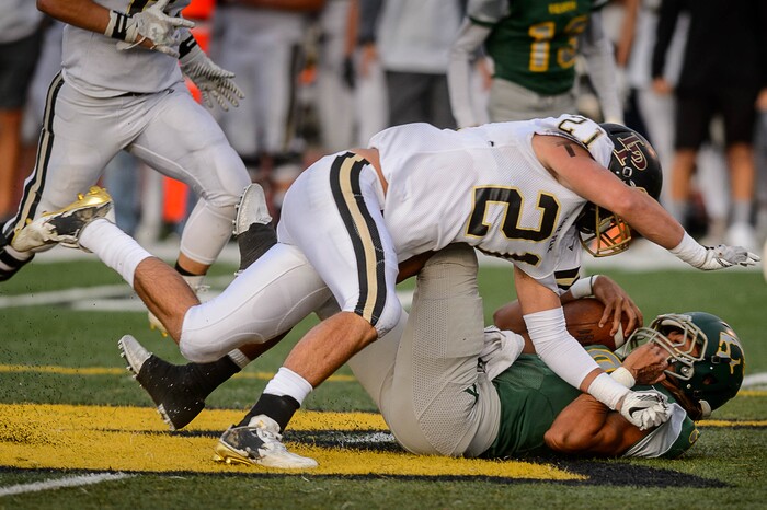 (Trent Nelson | The Salt Lake Tribune) Kearns quarterback Camden Wilbur is brought down by Lone Peak's Thomas Bateman as Kearns hosts Lone Peak, high school football, Thursday September 14, 2017.