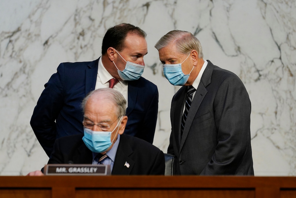 Senate Judiciary Committee Chairman Sen. Lindsey Graham, standing right, talks to Sen. Mike Lee, R-Utah., as Sen. Charles Grassley, R-Iowa, sits below, before a confirmation hearing for Supreme Court nominee Amy Coney Barrett before the Senate Judiciary Committee, Monday, Oct. 12, 2020, on Capitol Hill in Washington. (AP Photo/Susan Walsh, Pool)