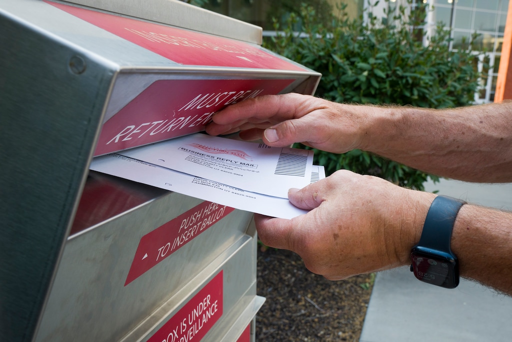 (Bethany Baker  |  The Salt Lake Tribune) A voter drops off two ballots at a ballot drop box at the Davis Conference Center in Layton on Monday, June 22, 2026.