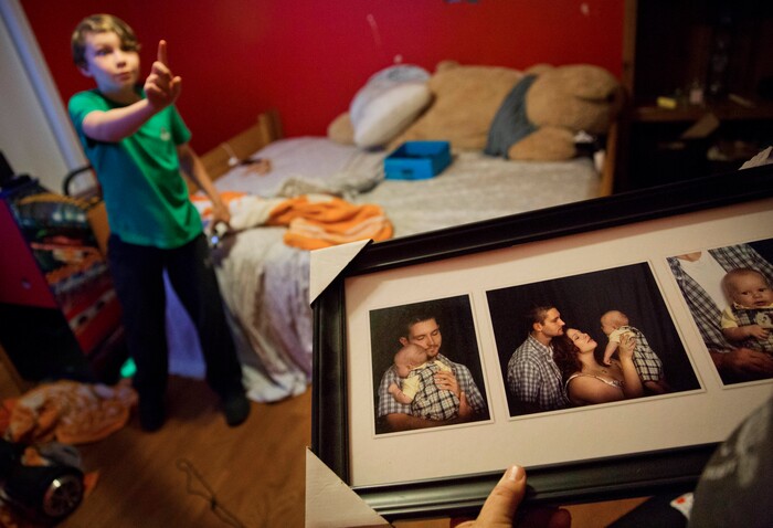 Photos of Robby Wilson, 10, left, as a baby with his parents, are held by his grandfather, Eddy Sweat, who is raising his grandson while the boy's parents are in jail in Jacksboro, Tenn., Monday, April 23, 2018. The absence of his mother, Krystle Sweat, has taken its toll on Robby, says his grandmother, Cathy Sweat. "Even at his happiest," she says, "he's not happy." (AP Photo/David Goldman)