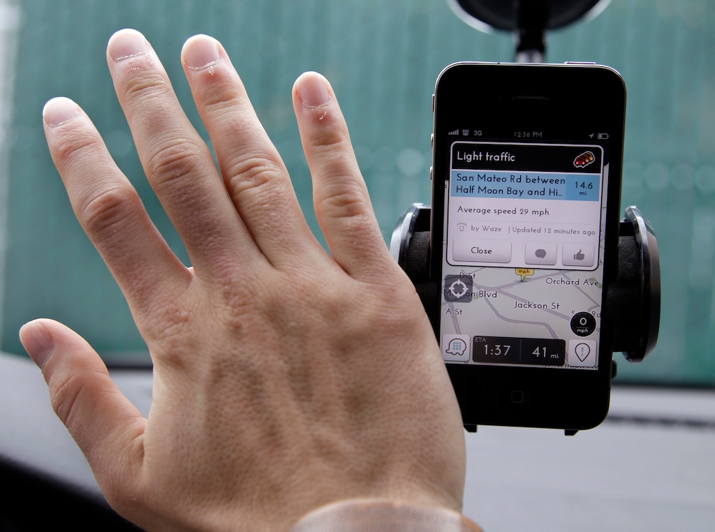 (Paul Sakuma | Associated Press) Ben Gleitzman waves his hand over a traffic and navigation app called Waze on his Apple iPhone in a Menlo Park, California.