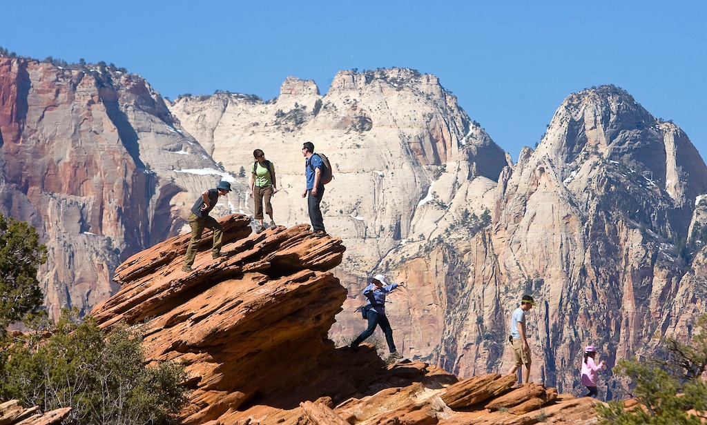 (Al Hartmann | Tribune file photo) Hikers play on the sandstone rocks from the Canyon Overlook Trail with a view into Zion Canyon. A new report says a proposed visitor center at Zion National Park's east entrance will bring broad economic benefits to Utah's Kane County.