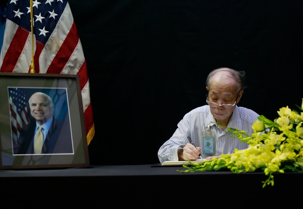 Pham Minh Chuc, an 81-year-old retiree, writes a book of condolences for Senator John McCain in Hanoi, Vietnam, Monday, Aug. 27, 2018. People in Vietnam are paying their respects to U.S. Sen. John McCain who was held as a prisoner of war in Vietnam and later was instrumental in bringing the wartime foes together. McCain died on Saturday. (AP Photo/Tran Van Minh)