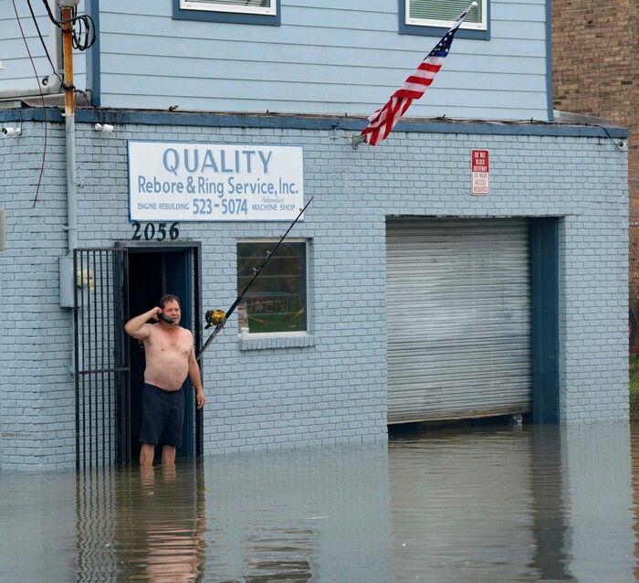 (Matthew Hinton | AP Photo) David Fox makes a call from his business on Poydras Street in New Orleans after flooding in New Orleans Wednesday, July 10, 2019. A storm swamped New Orleans streets and paralyzed rush-hour traffic Wednesday as concerns grew that even worse weather was on the way.