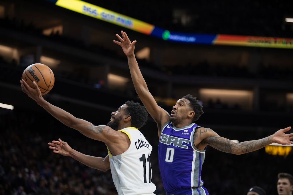 Utah Jazz guard Mike Conley (11) lays up a ball while defended by Sacramento Kings guard Malik Monk (0) during the second half of an NBA basketball game in Sacramento, Calif., Friday, Dec. 30, 2022. The Kings won 126-125. (AP Photo/José Luis Villegas)