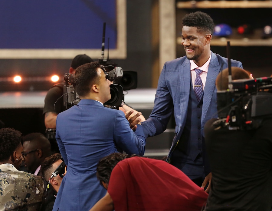 Arizona's Deandre Ayton, right, is congratulated by friends and family after he was picked first overall by the Phoenix Suns during the NBA basketball draft in New York, Thursday, June 21, 2018. (AP Photo/Kevin Hagen)
