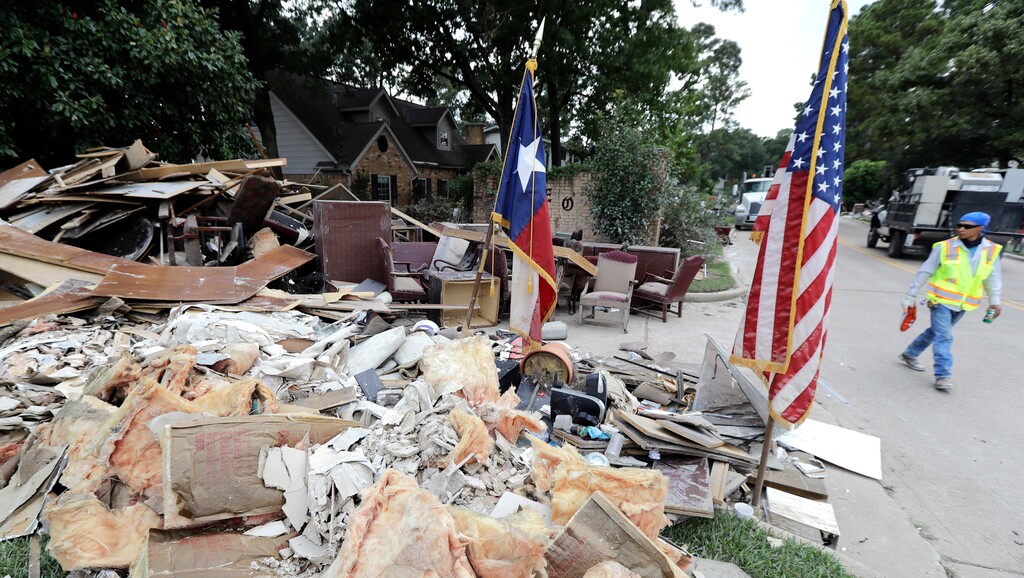 In this Sept. 5, 2017, photo, a worker walks past a pile of debris outside a business damaged by floodwaters in the aftermath of Hurricane Harvey in Spring, Texas. With federal disaster reserves running out, the House is swiftly moving to pass President Donald Trump’s request for a $7.9 billion first installment of relief for victims of Harvey. GOP leaders also hope to use the urgent Harvey aid bill to solve a far more vexing issue: Increasing the U.S. debt limit to permit the government to borrow freely again to cover its bills.  (AP Photo/David J. Phillip)