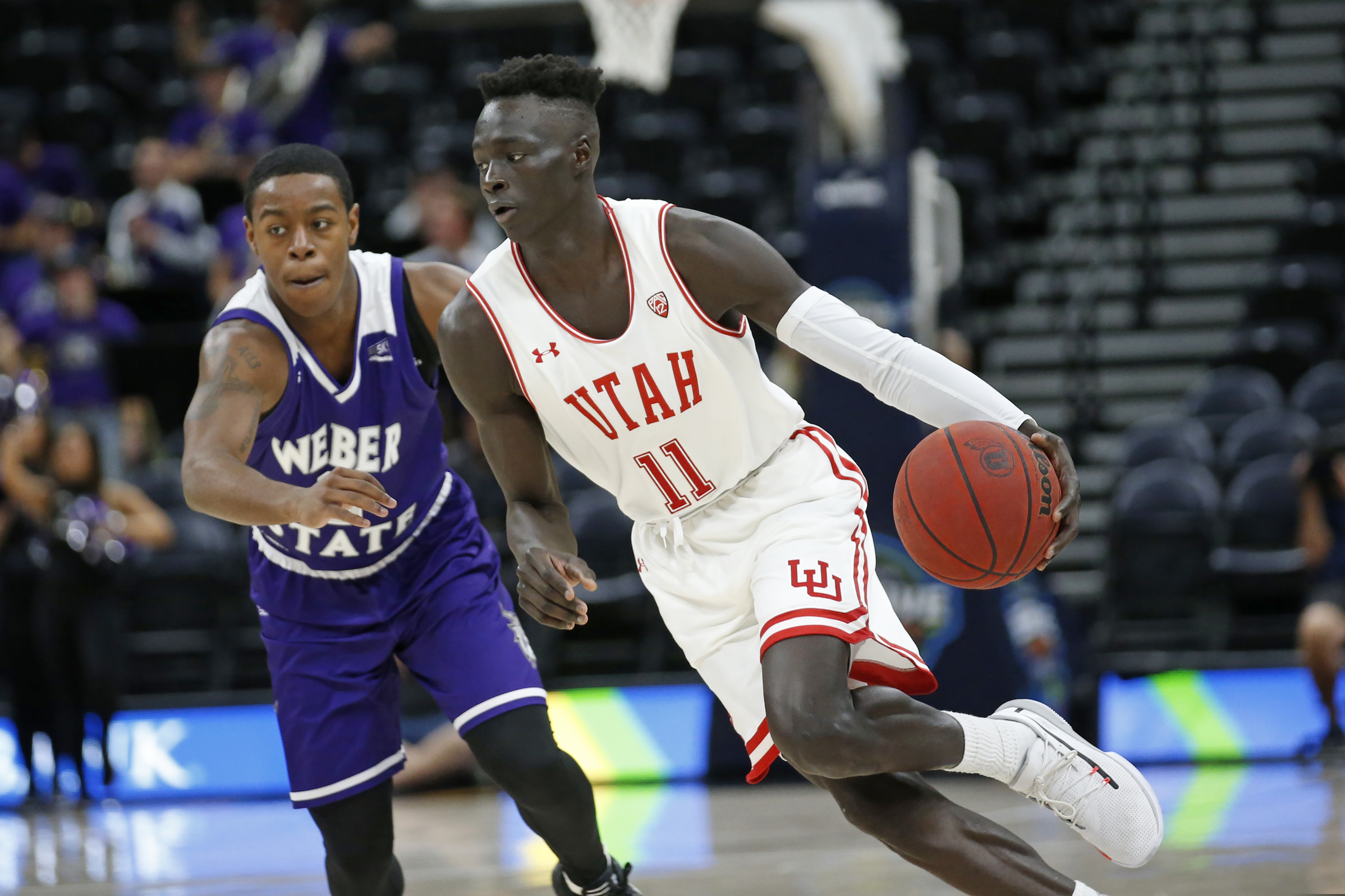 Utah guard Both Gach (11) drives around Weber State guard KJ Cunningham, rear, in the second half during an NCAA college basketball game Saturday, Dec. 14, 2019, in Salt Lake City. (AP Photo/Rick Bowmer)