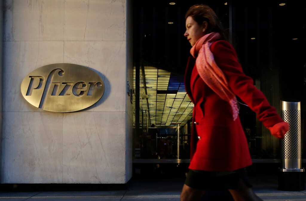 FILE - In this Monday, Nov. 23, 2015, file photo, a woman passes Pfizer's world headquarters, in New York. British regulators fined U.S. drugmaker Pfizer and distributor Flynn Pharma a record 89.4 million pounds ($112.7 million) Wednesday, Dec. 7, 2016 for increasing the cost of an epilepsy drug by as much as 2,600 percent. (AP Photo/Mark Lennihan, File)