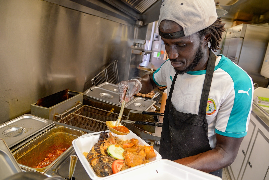 (Francisco Kjolseth  |  The Salt Lake Tribune)  Chef Pape Sall of the Balabe Senegalese food truck assembles the Tiep Jenn fried fish platter during Trolley Square Food Truck Night on Wednesday, July 17, 2019. Three of the vendors that showed up, along with four others, will vie for the title of Best New Food Truck on Aug. 3 at the Food Truck and Brewery Battle at The Gateway.