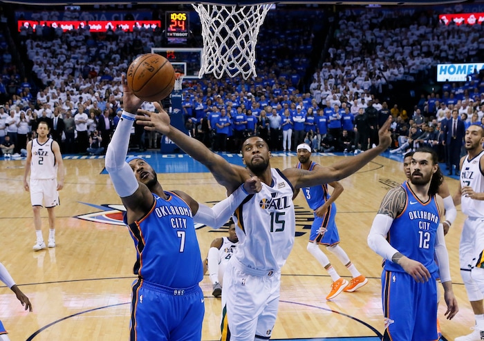 Oklahoma City Thunder forward Carmelo Anthony (7) and Utah Jazz forward Derrick Favors (15) reach for a rebound during the first half of Game 5 of an NBA basketball first-round playoff series in Oklahoma City, Wednesday, April 25, 2018. (AP Photo/Sue Ogrocki)
