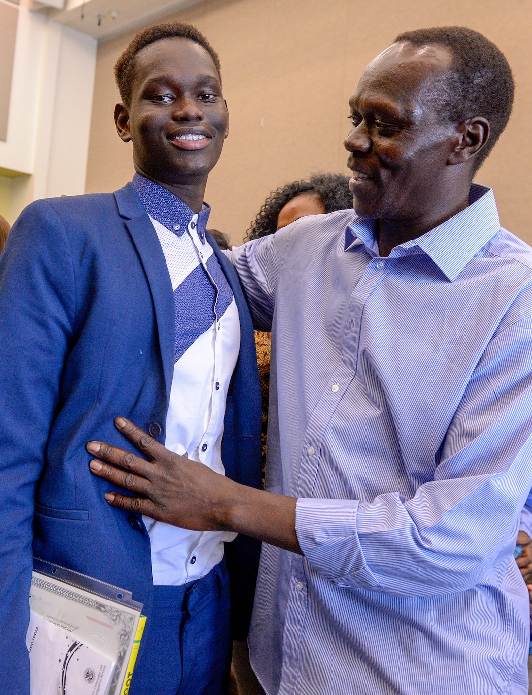 Leah Hogsten  |  The Salt Lake Tribune  Andrew Charles of Uganda is congratulated by his father Ben Charles at his youth naturalization ceremony at the Viridian Event Center in West Jordan, Monday, August 6, 2018. With hands on their heart 21 participants, ages 5 to 22, representing 8 countries, spoke the oath of citizenship as America's newest citizens.