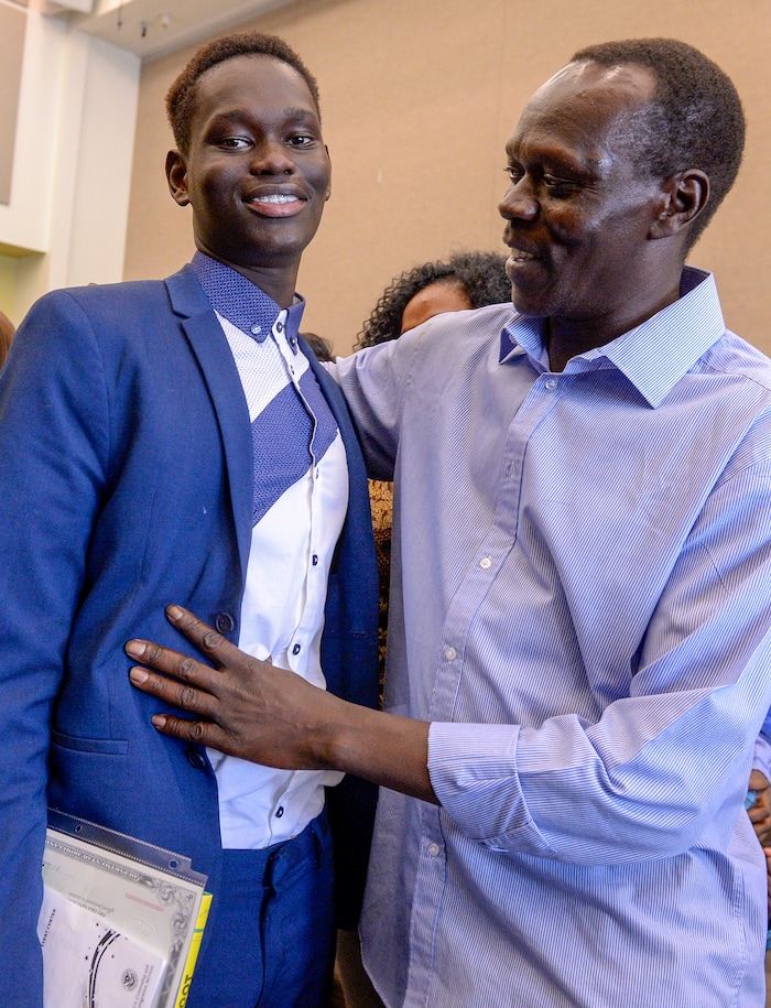 Leah Hogsten | The Salt Lake Tribune Andrew Charles of Uganda is congratulated by his father Ben Charles at his youth naturalization ceremony at the Viridian Event Center in West Jordan, Monday, August 6, 2018. With hands on their heart 21 participants, ages 5 to 22, representing 8 countries, spoke the oath of citizenship as America's newest citizens.