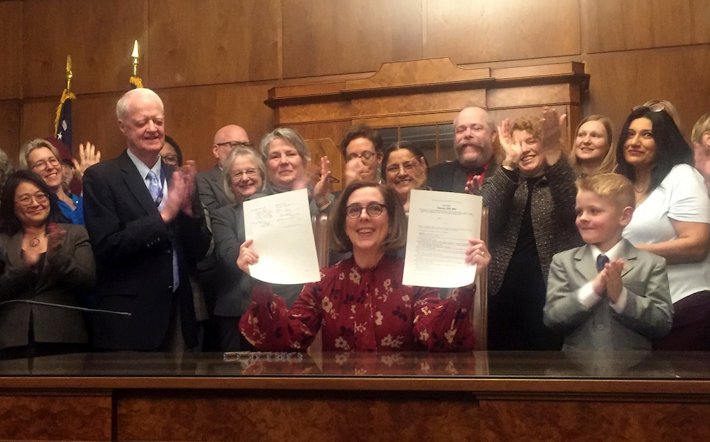 Oregon Gov. Kate Brown holds up a signed rent control bill on Thursday, Feb. 28, 2019, at the State Capitol in Salem, Ore. The state is now the first in the nation to impose mandatory rent control. Landlords would only be allowed to raise rent a limited amount once per year under the bill, and it is meant to address a housing crisis that has touched every corner of the state. (AP Photo/Sarah Zimmerman)