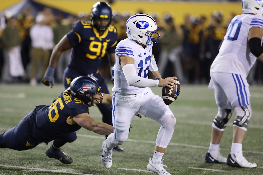 (Chris Jackson | AP) BYU quarterback Jake Retzlaff (12) is rushed by West Virginia's Edward Vesterinen (96) on Saturday in Morgantown, W.Va.