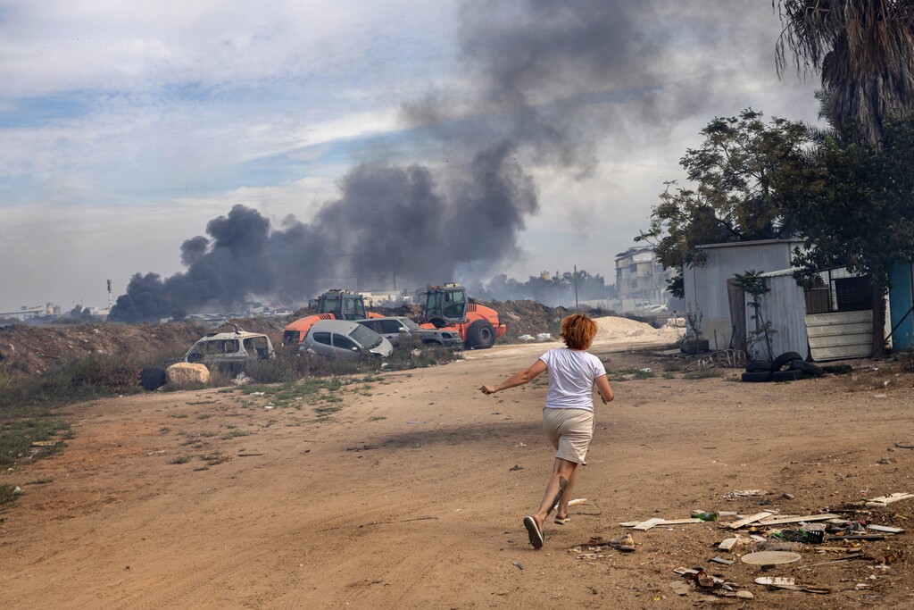 (Tamir Kalifa | The New York Times) Evgenia Simanovich runs to the family home's reinforced concrete shelter, moments after rocket sirens sounded in Ashkelon, Israel on Saturday, Oct. 7, 2023.