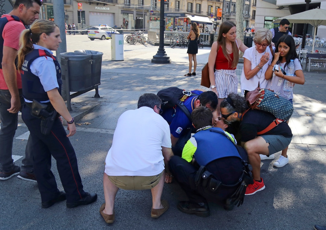 A person is treated in Barcelona, Spain, Thursday, Aug. 17, 2017 after a white van jumped the sidewalk in the historic Las Ramblas district, crashing into a summer crowd of residents and tourists and injuring several people, police said. (AP Photo/Oriol Duran)