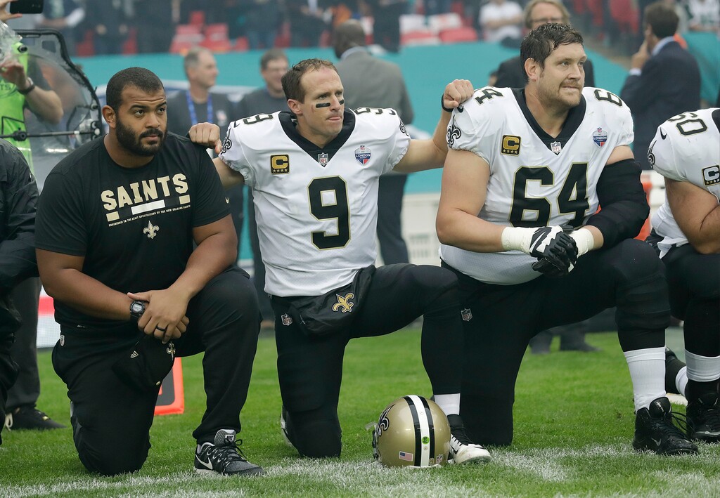 New Orleans Saints quarterback Drew Brees (9) kneels down with teammates before the U.S. national anthem was played ahead of an NFL football game against the Miami Dolphins at Wembley Stadium in London, Sunday Oct. 1, 2017. Saints players then stood when the anthem was played. (AP Photo/Tim Ireland)