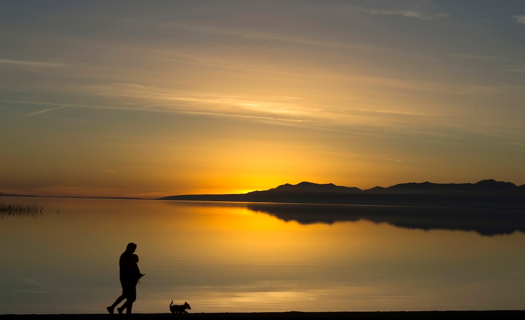 (Rick Egan | The Salt Lake Tribune) Tyler and Gracie Claires of Layton, enjoy the sunset as they walk along the shore of Willard Bay Reservoir with their dog Jedi, Saturday, January 13, 2018. A new law will require visitors to any Wildlife Management Area, such as Willard Bay Upland Game Area, to be registered in a state database.