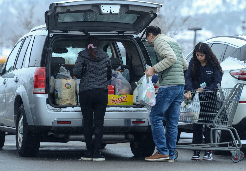 (Leah Hogsten  |  The Salt Lake Tribune)  A family loads a cart full of groceries into their car outside of Walmart in Park City, March 25, 2020.