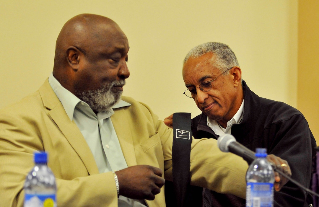 John Griffen, right, ties a black armband on the arm of his former teammate Mel Hamilton prior to The Black 14 panel discussion in the Central Ballroom Tuesday November 3, 2009 in Laramie, Wyo. The discussion marks the 40-year anniversary when in 1969 14 Wyoming football players were kicked off the team as they planned on wearing black armbands during a game against BYU. (Photo by Andy Carpenean/Laramie Boomerang)