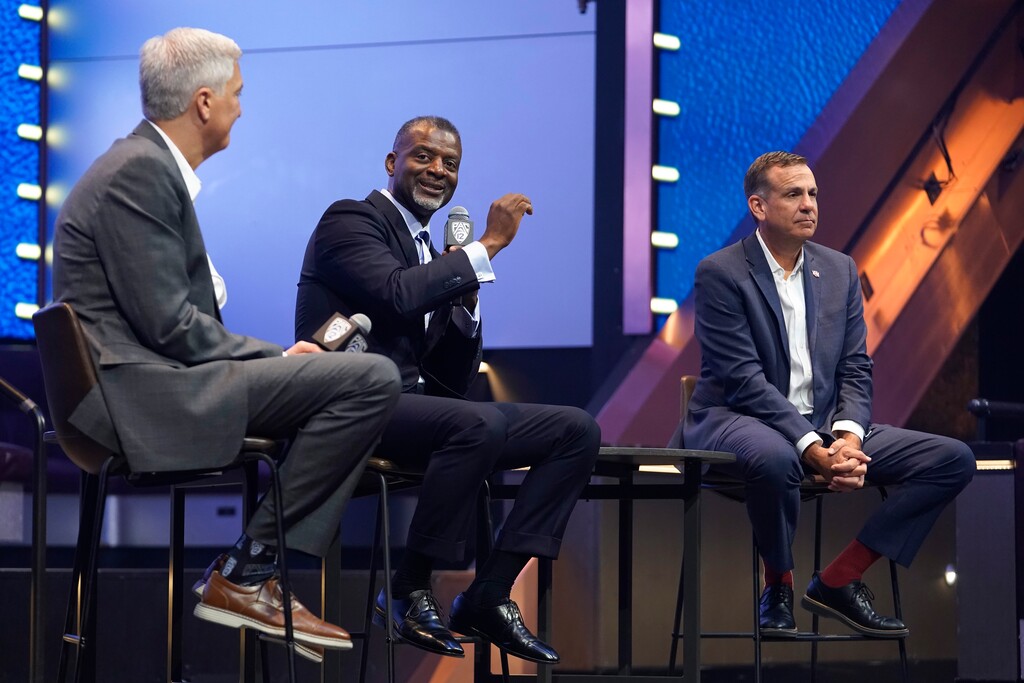 (Lucas Peltier | AP) Pac-12 associate commissioner Merton Hanks answers questions with Pac-12 commissioner George Kliavkoff, left, and Utah athletic director Mark Harlan at the NCAA college football Pac-12 media day Friday, July 21, 2023, in Las Vegas.