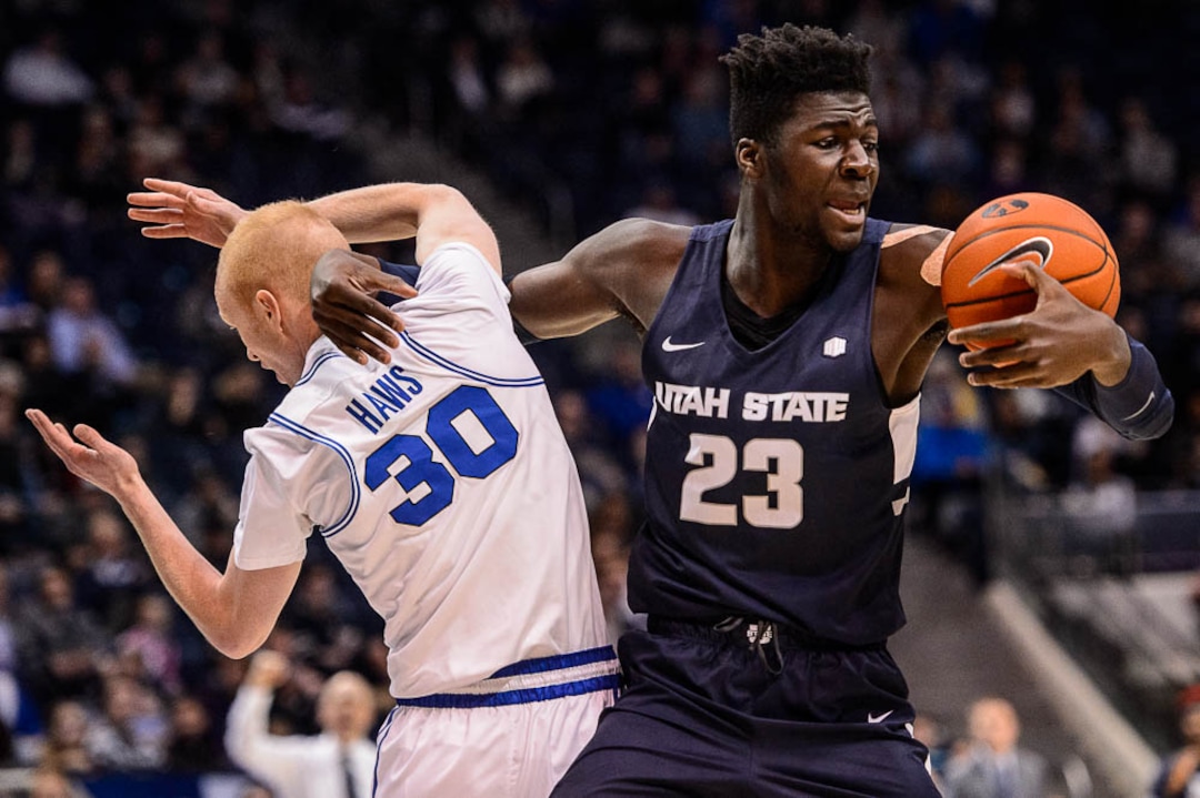 (Trent Nelson | The Salt Lake Tribune)  Utah State Aggies center Neemias Queta (23) pulls down a rebound with Brigham Young Cougars guard TJ Haws (30) at left as BYU hosts Utah State, NCAA basketball in Provo on Wednesday Dec. 5, 2018.