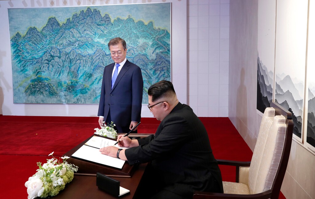 North Korean leader Kim Jong Un signs a guest book watched by South Korean President Moon Jae-in, top, inside the Peace House at the Peace House at the border village of Panmunjom in Demilitarized Zone Friday, April 27, 2018. Their discussions will be expected to focus on whether the North can be persuaded to give up its nuclear bombs. (Korea Summit Press Pool via AP)