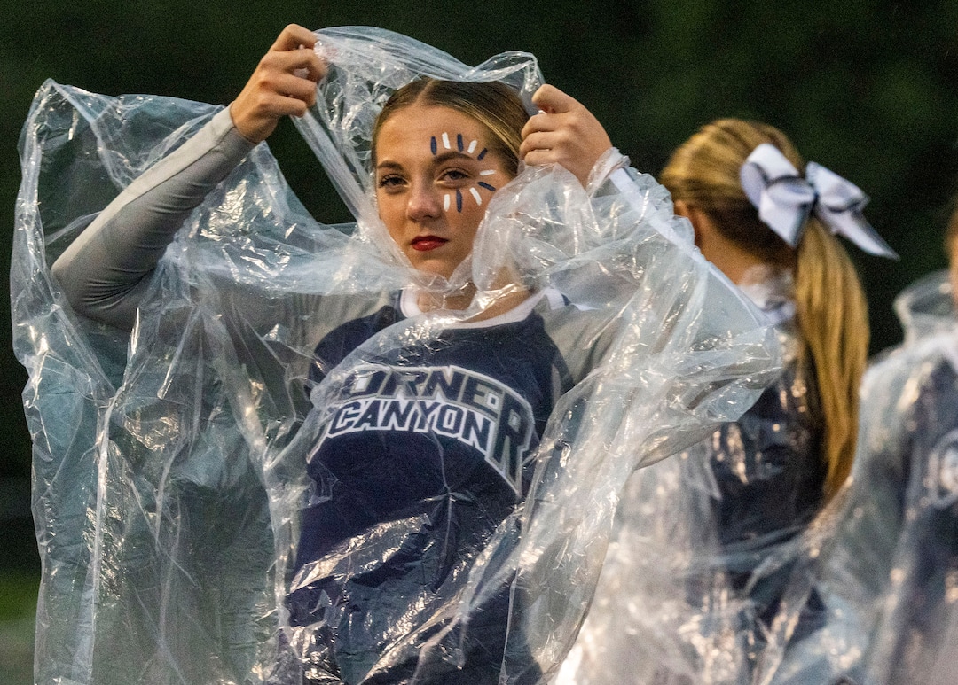 (Rick Egan | The Salt Lake Tribune) A Corner Canyon cheer leader tries watch the game through the wind and the rain, in prep football action between Corner Canyon Chargers and the East Leopards, on Saturday, Aug. 21, 2021.