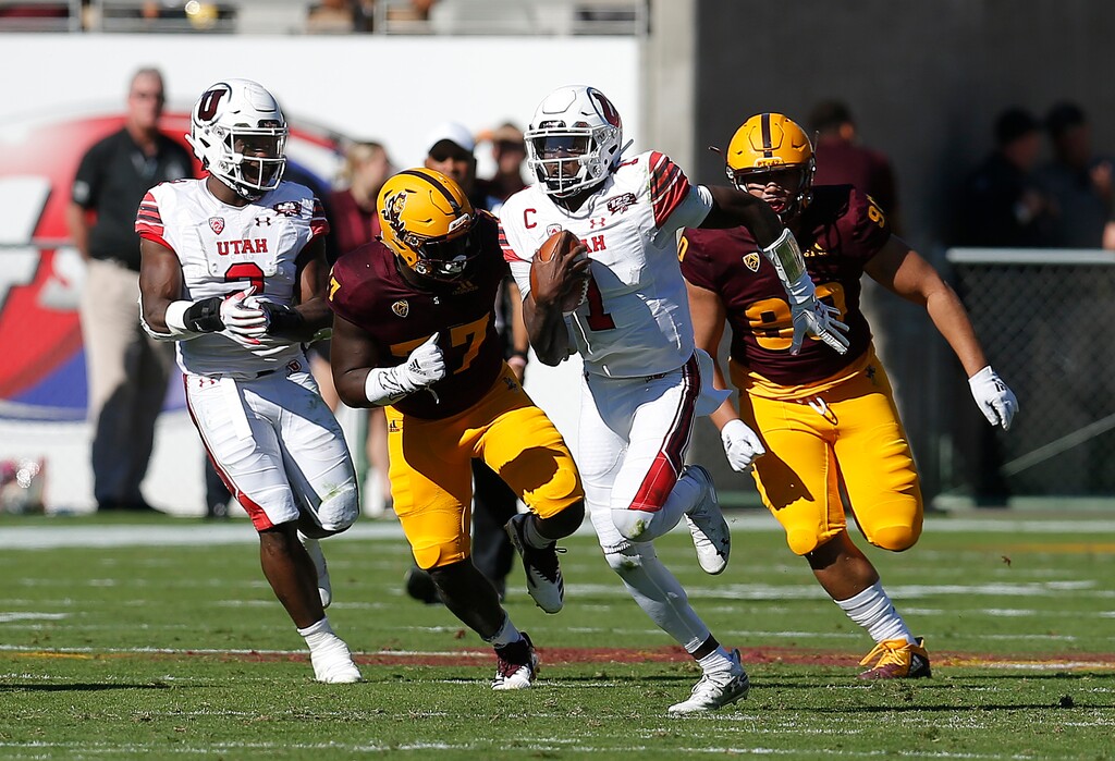 (AP Photo/Rick Scuteri) Utah quarterback Tyler Huntley (1) runs away from Arizona State defenders in the first half during an NCAA college football game Saturday in Tempe, Ariz.