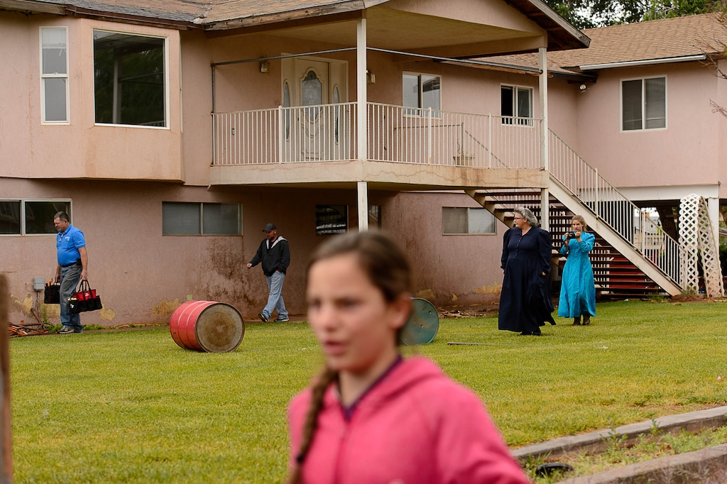 Trent Nelson | The Salt Lake Tribune
FLDS member Shannon Darger, second from left, looks on as UEP Trust agent Ted Barlow and locksmith Kelvin Holdaway begin to change the locks on her Colorado City, AZ, home, Wednesday May 10, 2017. Like other FLDS members, Darger considers working with the UEP Trust to be against her religious beliefs and has chosen to move her family out of state rather than sign an occupancy agreement with the trust.