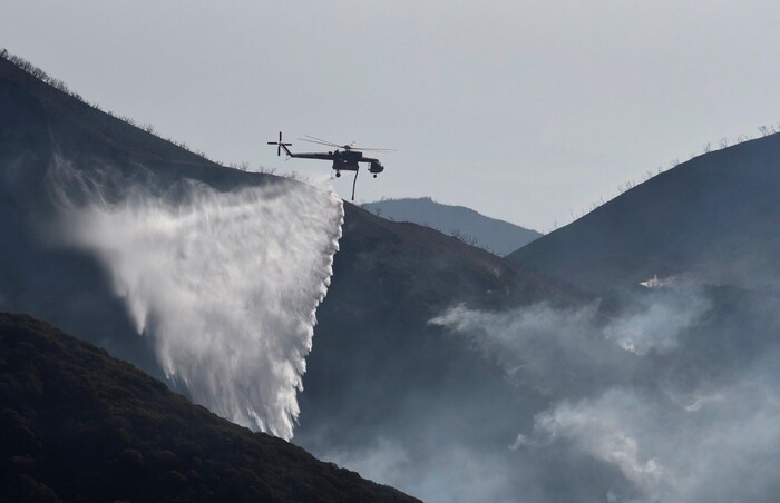 (Mike Eliason | Santa Barbara County Fire Department via AP) In this photo provided by the Santa Barbara County Fire Department, a Sikorsky S-64 Skycrane makes a water drop on hot spots along the hillside east of Gibraltar Road in Santa Barbara, Calif., Sunday morning, Dec. 17, 2017. One of the largest wildfires in California history is now 40 percent contained but flames still threaten coastal communities as dry, gusty winds are predicted to continue.