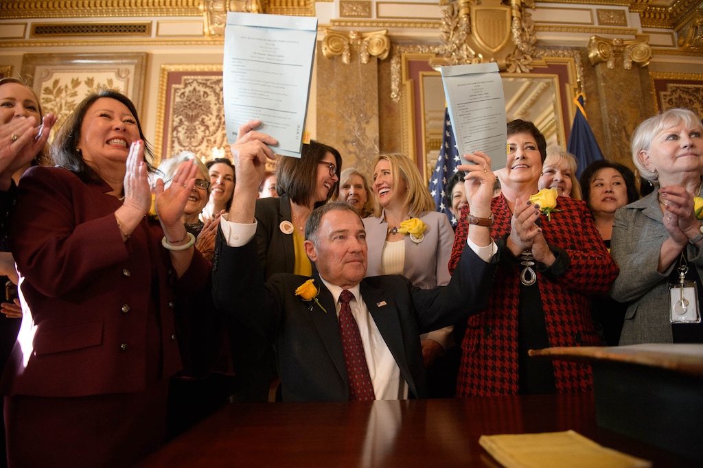 (Trent Nelson | Tribune file photo) Surrounded by female legislators, Utah Gov. Gary Herbert holds up two signed copies of a joint resolution celebrating women’s suffrage in Utah, part of the celebration of suffrage at the state Capitol in Salt Lake City on Wednesday, Feb. 12, 2020. To the right of Herbert is First Lady Jeanette Herbert.
