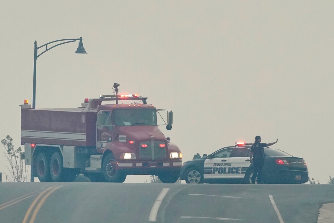 (George Frey  |  for The Salt Lake Tribune) An officer hold traffic for a firetruck to make its way to homes in south Saratoga Springs due to a wildfire on June 28, 2020.